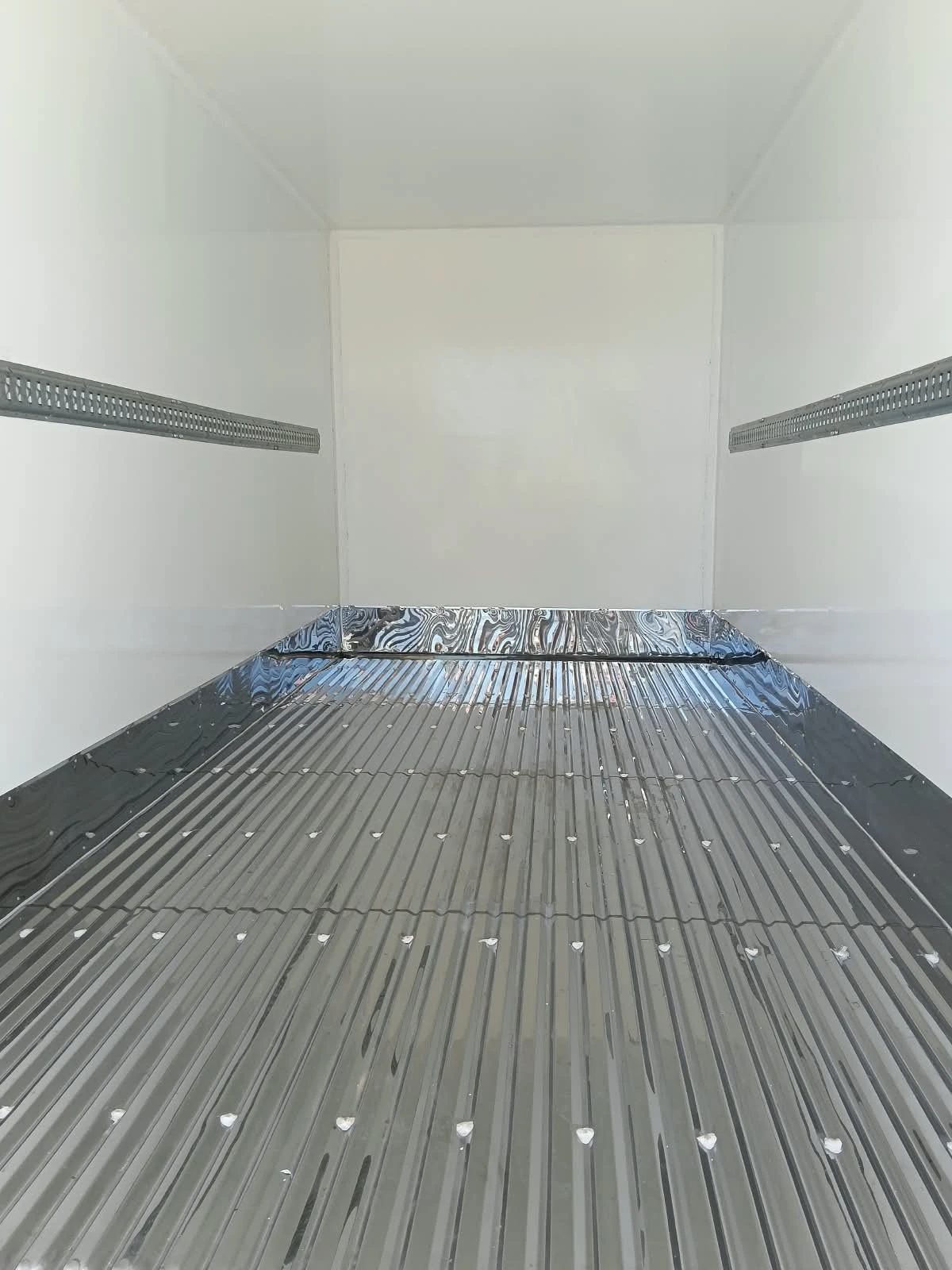 Interior de furgón refrigerado con piso en acero inoxidable y rieles de carga