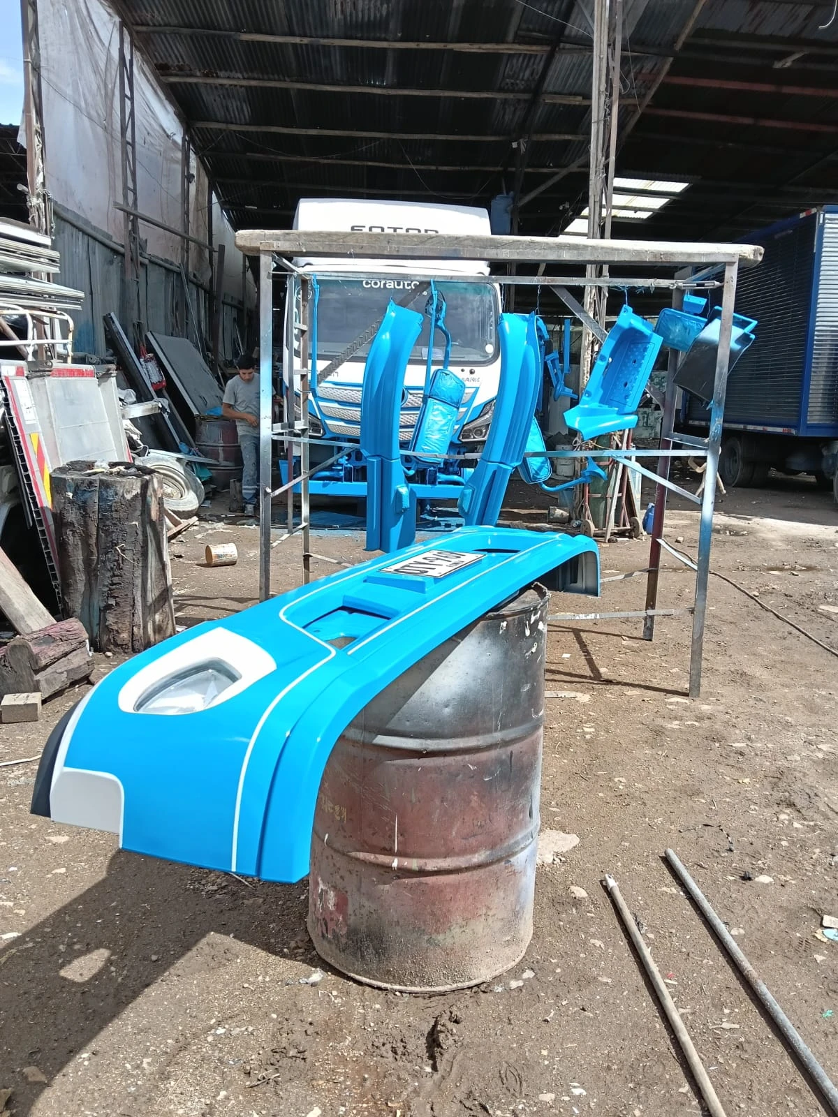 Piezas de cabina recién pintadas en azul secándose en el taller